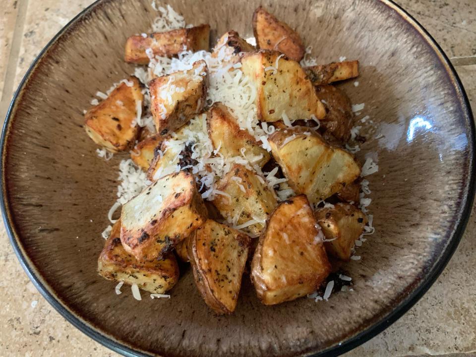 Roasted potatoes on brown plate with cheese on top