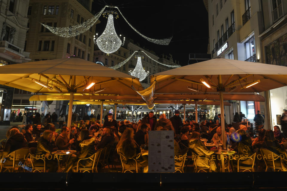 People sit at an outdoor cafe on a street decorated with Christmas lights in Vienna, Austria, Saturday, Nov. 20, 2021. The Austrian government announced a nationwide lockdown that will start Monday and comes as average daily deaths have tripled in recent weeks and hospitals in heavily hit states have warned that intensive care units are reaching capacity. (AP Photo/Vadim Ghirda)