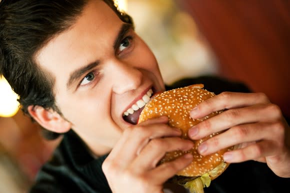 A young man takes a bite of a burger.