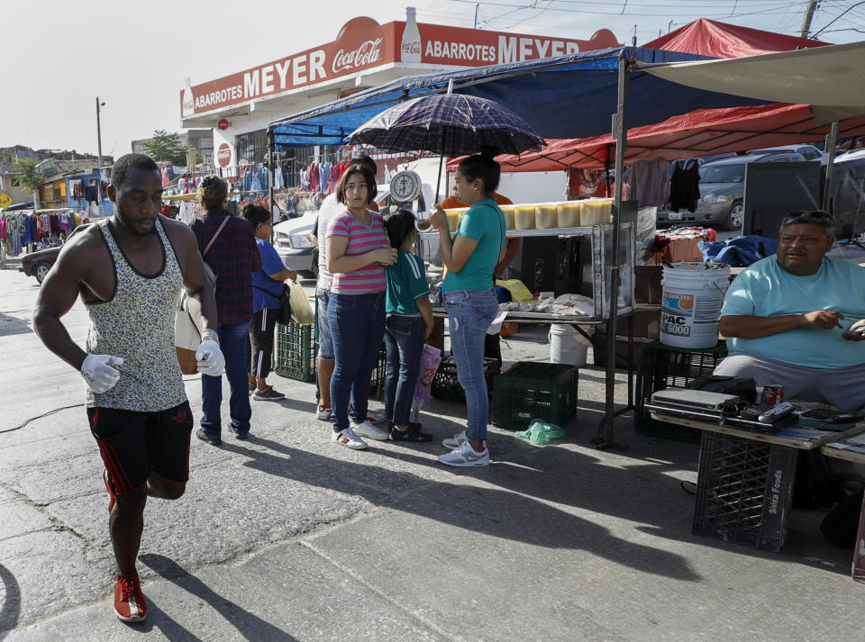 In this July 31, 2019, photo, Alphat, of Uganda runs through a neighborhood surrounding the El Buen Pastor shelter for migrants in Cuidad Juarez, Mexico. Alphat runs relentlessly, and seemingly effortlessly. People stop to stare, surprised to see a black man with ham-sized biceps and impossibly broad shoulders running through this city, which has long been a magnet for migrants. (AP Photo/Gregory Bull)