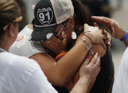 FILE - In this Oct. 1, 2018 file photo people embrace Norma Felix at a prayer service on the anniversary of the Oct.1, 2017 mass shooting in Las Vegas. Two years after a shooter rained gunfire on country music fans from a high-rise Las Vegas hotel, MGM Resorts International reached a settlement that could pay up to $800 million to families of the 58 people who died and hundreds of others who were injured, attorneys announced Thursday, Oct. 3, 2019. (AP Photo/John Locher,File)
