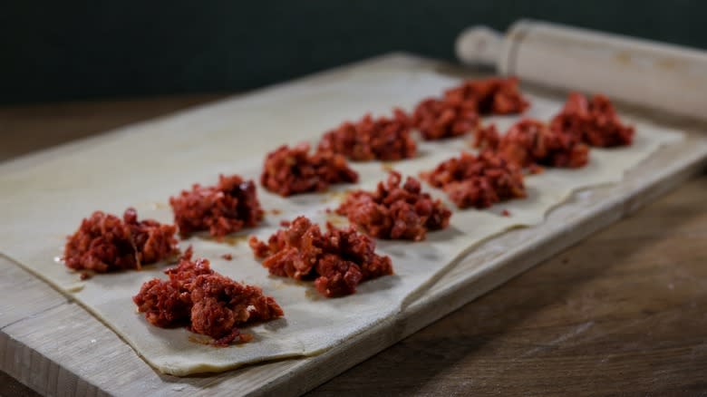 piles of ravioli filling on sheet of pasta