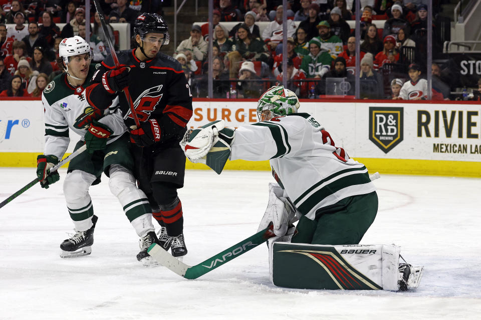 Minnesota Wild goaltender Filip Gustavsson, right, snares the puck in front of Carolina Hurricanes' Seth Jarvis (24) and teammate Brock Faber (7) during the second period of an NHL hockey game in Raleigh, N.C., Sunday, Jan. 21, 2024. (AP Photo/Karl B DeBlaker)