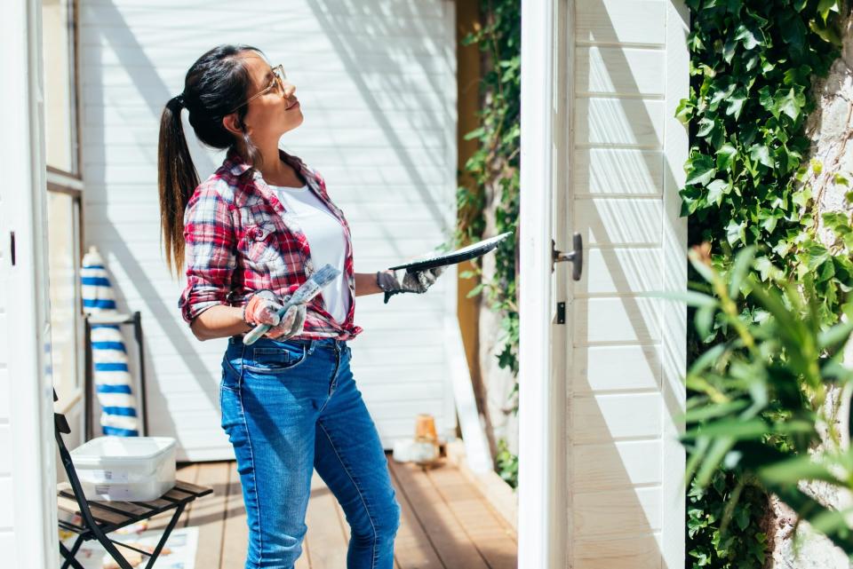 woman painting home exterior