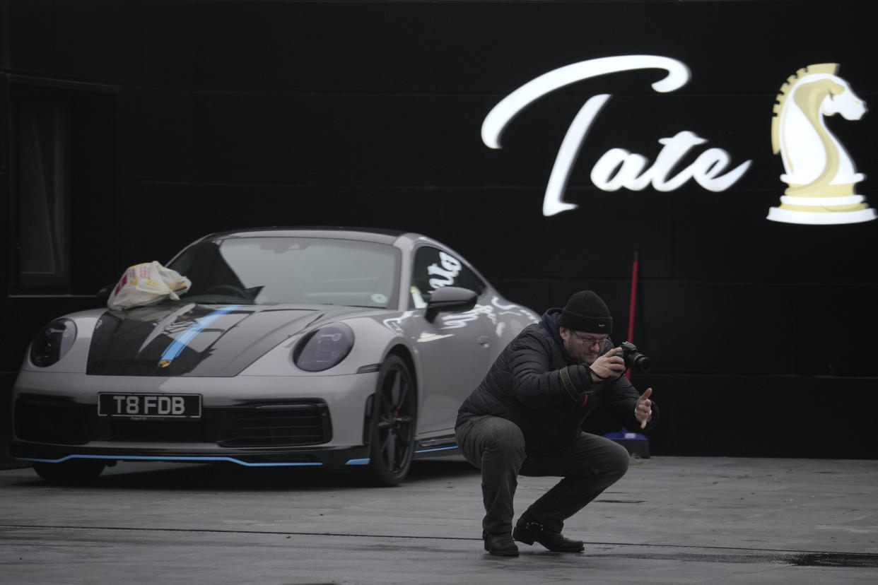 A man takes pictures backdropped by a UK registered luxury vehicle which was seized in a case against media influencer Andrew Tate, is towed away, on the outskirts of Bucharest, Romania, Saturday, Jan. 14, 2023. Prosecutors seized several luxury vehicles after Tate lost a second appeal this week at a Bucharest court, where he challenged the seizure of assets in the late December raids, including properties, land, and a fleet of luxury cars. More than 10 properties and land owned by companies registered to the Tate brothers have also been seized so far. (AP Photo/Vadim Ghirda)