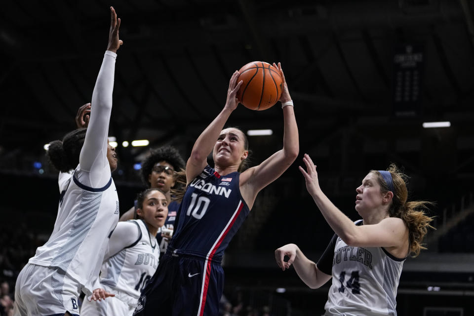 UConn guard Nika Muhl (10) shoots between Butler forward Kelsy Taylor (44) and forward Rachel McLimore (14) during the second half of an NCAA college basketball game in Indianapolis, Tuesday, Jan. 3, 2023. (AP Photo/Michael Conroy)