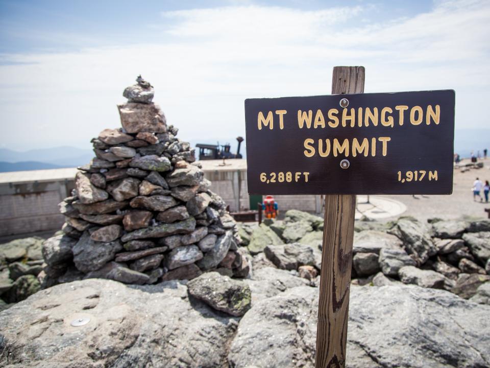Mount Washington Summit sign near a large triangular pile of rocks New Hampshire