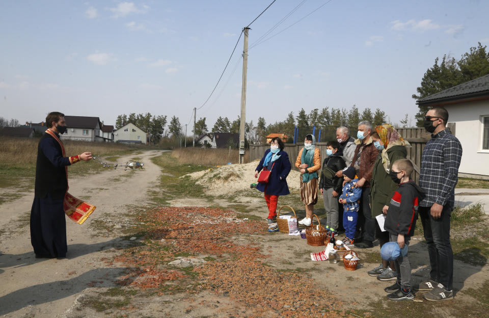 A priest of the Ukrainian Orthodox Church Nazariy, wearing a face mask to protect against coronavirus, blesses family members on the Easter eve near their house in the village of Nove close to capital Kyiv, Ukraine, Saturday, April, 18, 2020. All the Ukrainian churches have been closed for people because of COVID-19 outbreak, and believers wait for the priest right near their houses. For Orthodox Christians, this is normally a time of reflection, communal mourning and joyful release, of centuries-old ceremonies steeped in symbolism and tradition. But this year, Easter - by far the most significant religious holiday for the world's roughly 300 million Orthodox - has essentially been cancelled. (AP Photo/Efrem Lukatsky)