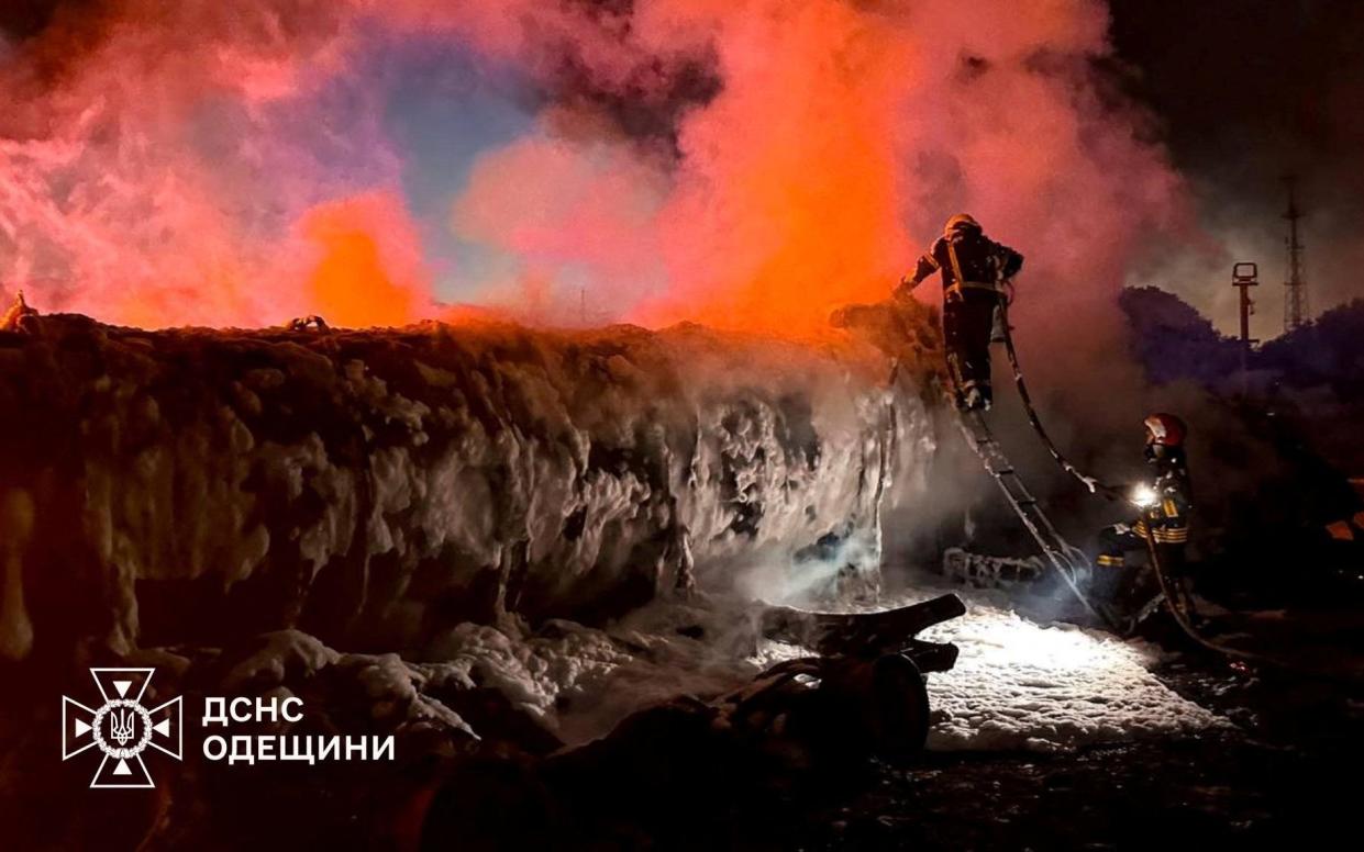 Members of emergency services work as smoke rises in the aftermath of a Russian drone strike