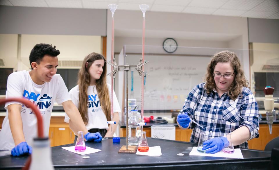 Jordan Mader, assistant professor of chemistry, talks to members of MAPS while doing a project.