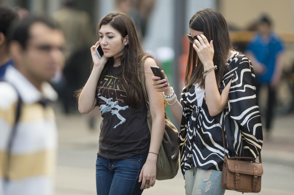 Two women use their cellphone while walking on Yonge Street in Toronto. (Carlos Osorio/Toronto Star via Getty Images)