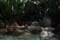 A woman rests along the rocks at the edge of the swimming pool at Kamalaya Wellness Sanctuary, Koh Samui, Thailand.