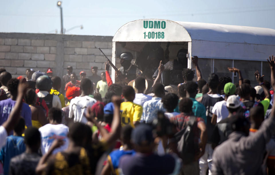 In this Dec. 10, 2018 photo, police guard an alleged gang member to keep the crowd from attacking him outside a police station in the La Saline slum of Port-au-Prince, Haiti. Residents believe the arrested man is one of the perpetrators of a Nov. 13 massacre that killed at least 20 people in La Saline slum. (AP Photo/Dieu Nalio Chery)