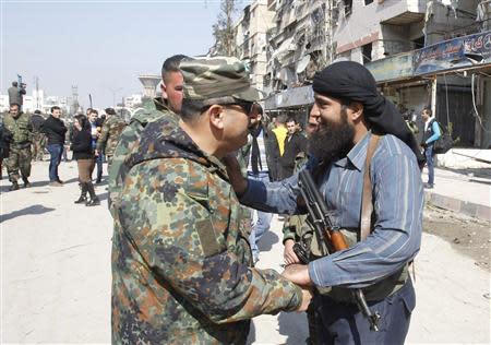 A member of Syria's armed opposition forces (R) chats with an officer from the forces loyal to Syria's President Bashar al-Assad in Babila town, southeast Damascus February 17, 2014, after a local ceasefire agreement was reached. Picture taken during a guided tour by the Syrian Army. REUTERS/Khaled al-Hariri