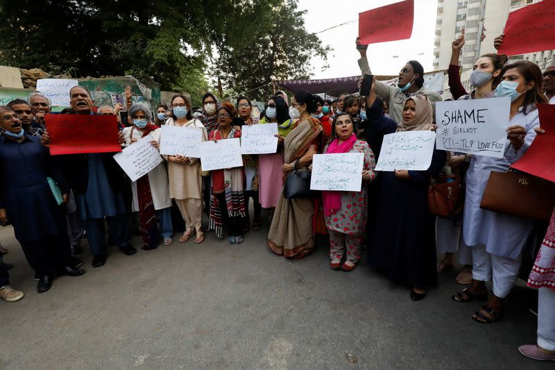 People carry signs, condemning the lynching of the Sri Lankan manager of a garment factory after an attack on the factory in Sialkot, during a protest in Karachi