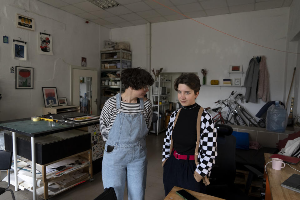 Jenya Polosina, left, Anna Ivanenko, right, both Kyiv-based artists, stand in their studio in Kyiv, Ukraine, Sunday, April 30, 2023. Polosina and Ivanenko appeared Monday, May 1, 2023, from Kyiv via video link on a screen at an art opening for an exhibit called "Our Fire is Stronger Than Your Bombs" at Saint Anselm College, in Manchester, N.H., Monday, May 1, 2023. Polosina and Ivanenko are among a number of Ukrainian artists with works in the exhibit. (AP Photo/Vasilisa Stepanenko)