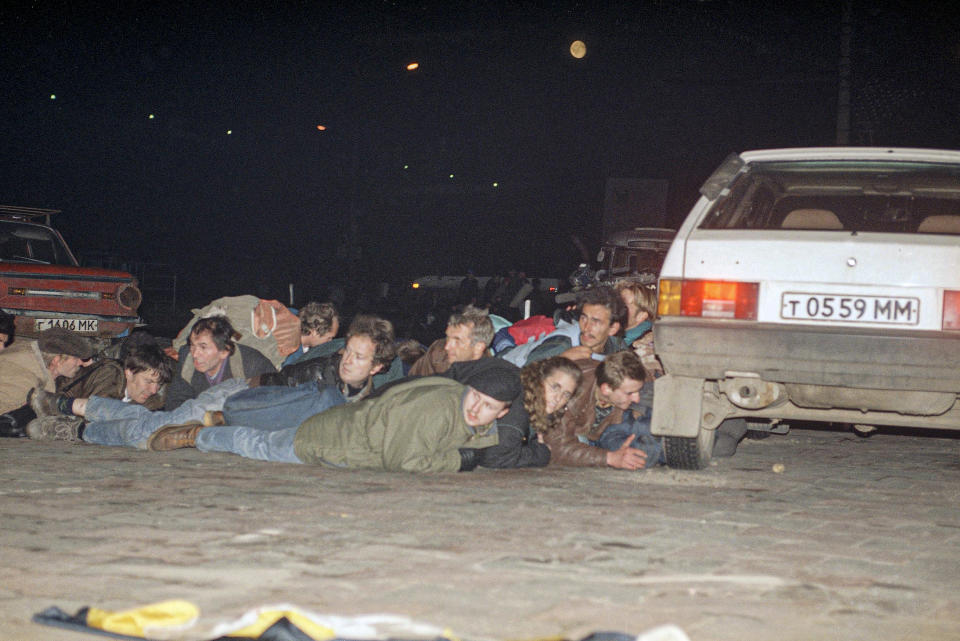 FILE - Hard-liners take cover behind a car at the Ostankino TV Center in Moscow during a shootout with government commandos inside the building on Oct. 3, 1993. The October 1993 violent showdown between the Kremlin and supporters of the rebellious parliament marked a watershed in Russia's post-Soviet history. (AP Photo/Igor Mikhalev, File)