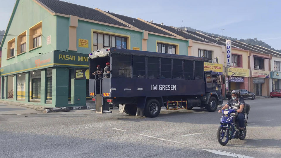 In this image taken from a video, an immigration truck with security and unidentified people drives on a road that leads to Lumut Naval Base Tuesday, Feb. 23, 2021 in Lumut, Malaysia. A Malaysian court Tuesday ordered a halt to the planned deportation of 1,200 Myanmar migrants to hear an appeal by two human rights groups, which say the migrants included refugees, asylum seekers and minors. (AP Photo)