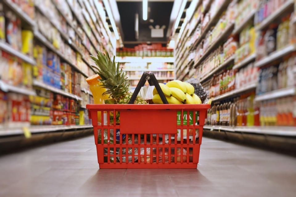 A full basket sits in the middle of an aisle in a grocery store