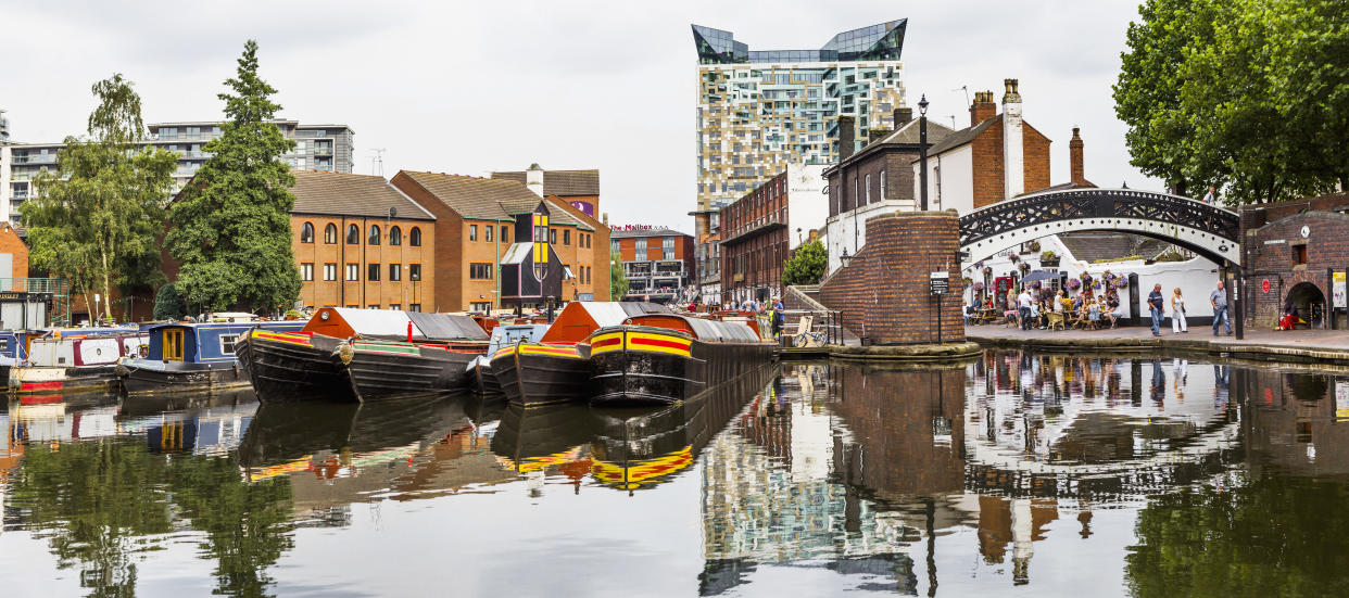 A canal basin in the centre of the town of Birmingham, with people eating outside a restaurant in the background. (Getty Images)