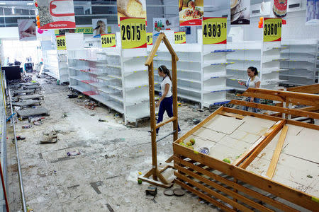 Workers walk next to empty shelves in a supermarket after it was looted in San Cristobal, Venezuela May 17, 2017. REUTERS/Carlos Eduardo Ramirez