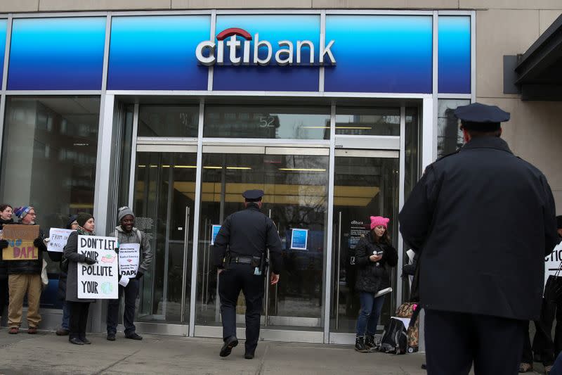 Police stand guard as activists hold placards outside a Citibank branch in protest against banks funding the Dakota Access Pipeline during a Divestment Day rally in Manhattan