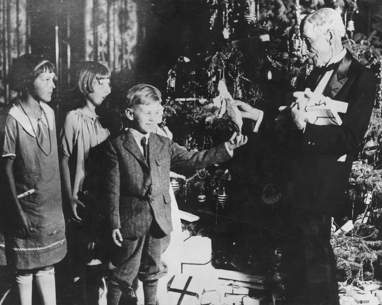 American oil magnate and philanthropist, John Davidson Rockefeller (1839 - 1937) handing out Christmas presents to a group of children.