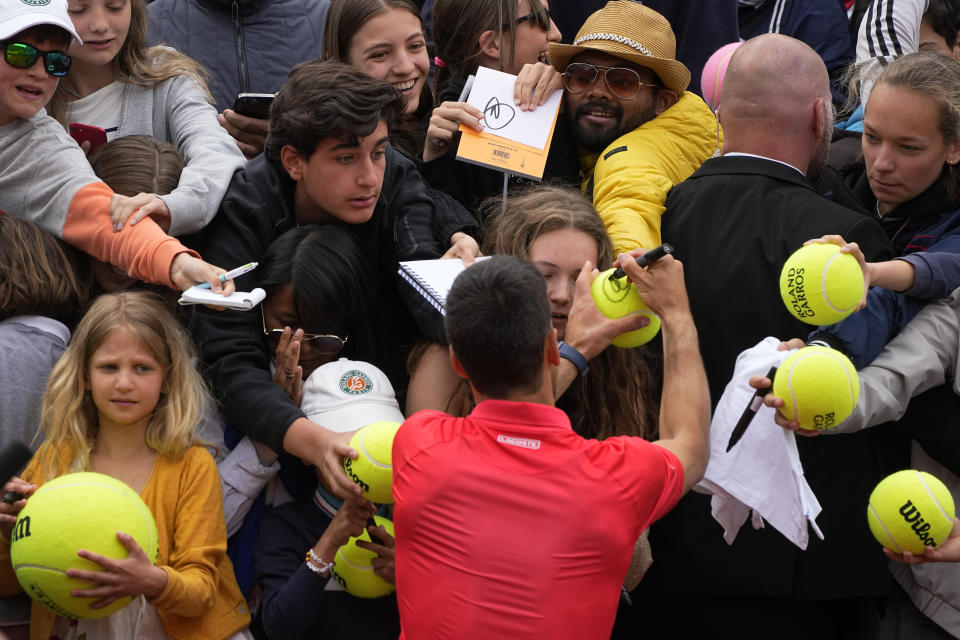 Serbia's Novak Djokovic signs autographs after winning against Argentina's Diego Schwartzman in three sets, 6-1, 6-3, 6-3, in their fourth round match at the French Open tennis tournament in Roland Garros stadium in Paris, France, Sunday, May 29, 2022. (AP Photo/Michel Euler)