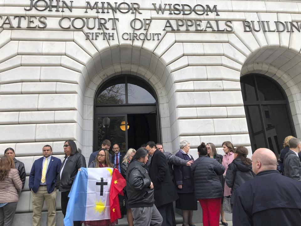 FILE -Rosa Soto Alvarez, of Tucson,, holds a flag of the Pascua Yaqui Tribe as she and other Native Americans stand outside the federal appeals court in New Orleans, Wednesday, Jan. 22, 2020. Parts of a federal law giving Native American families preference in the adoption of Native American children were effectively struck down Tuesday, April 6, 2021 by a sharply divided federal appeals court, a defeat for tribal leaders who said the 1978 law was important to protecting their families and culture. The U.S. Supreme Court will hear arguments, Wednesday, Nov. 9, 2022 on the most significant challenge to the Indian Child Welfare Act that gives preference to Native American families in foster care and adoption proceedings of Native American children since it passed in 1978. (AP Photo/Kevin McGill, File)