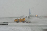 Workers clear the runway as snow falls at John F. Kennedy International Airport, Tuesday, Feb. 13, 2024, in New York. (AP Photo/Frank Franklin II)