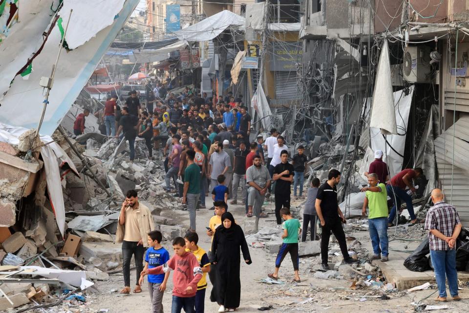 Palestinians walk amid the rubble of destroyed and damaged buildings in the heavily bombarded city center of Khan Yunis in the southern Gaza Strip following overnight Israeli shelling, on October 10, 2023. (Photo by SAID KHATIB / AFP) (Photo by SAID KHATIB/AFP via Getty Images)