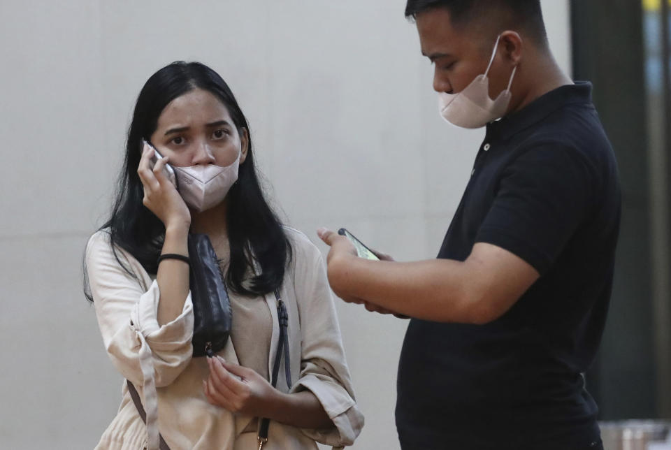 Relatives of passengers use their mobile phones at a crisis center set up following a report that a Sriwijaya Air passenger jet has lost contact with air traffic controllers shortly after take off, at Soekarno-Hatta International Airport in Tangerang, Indonesia,Saturday, Jan. 9, 2021. The Boeing 737-500 took off from Jakarta with 56 passengers and six crew members onboard, and lost contact with the control tower a few moments later. (AP Photo/Tatan Syuflana)