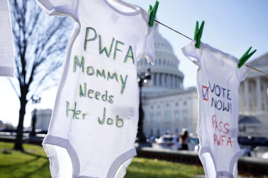 Onesies hung on a clothesline outside the U.S. Capitol saying "PWFA Mommy Needs Her Job" and "Vote Now Pass PWFA"