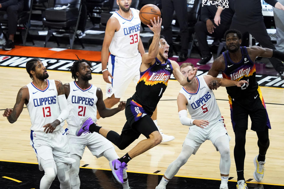 Phoenix Suns guard Devin Booker (1) is fouled driving to the basket as Los Angeles Clippers guard Patrick Beverley (21), forward Paul George (13), and guard Luke Kennard (5) defend during the first half of game 5 of the NBA basketball Western Conference Finals, Monday, June 28, 2021, in Phoenix. (AP Photo/Matt York)