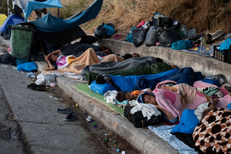 Refugees and migrants from the destroyed Moria camp sleep on the side of a road, on the island of Lesbos