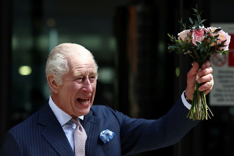 El rey Carlos III sonríe con un ramo de flores en la mano al saludar a los curiosos durante una visita a la sección oncológica de un hospital, el 30 de abril de 2024 en Londres (Henry Nicholls)