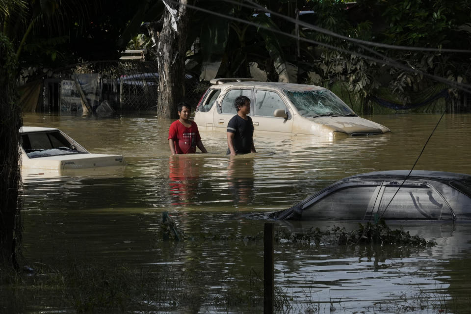 Residents wade through a flooded road in their housing area in Shah Alam, on the outskirts of Kuala Lumpur, Malaysia, Monday, Dec. 20, 2021. Rescue services on Monday worked to free thousands of people trapped by Malaysia's worst flooding in years after heavy rains stopped following more than three days of torrential downpours in the capital and around the country. (AP Photo/Vincent Thian)