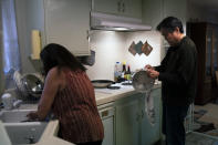 Kerry Osaki, right, helps his wife, Lena Adame, in the kitchen in Fountain Valley, Calif., Wednesday, Nov. 25, 2020. For years, Osaki went with his mother to his aunt's house for Thanksgiving to celebrate with family. His wife spent the holiday cooking a spread of turkey and stuffing with her relatives. This year, both of their traditions have fallen to the pandemic that took the life of Osaki's 93-year-old mother.(AP Photo/Jae C. Hong)