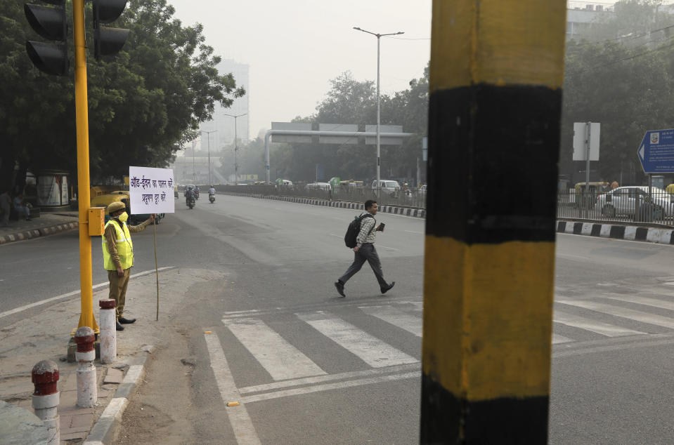 A policewoman wears a pollution mask and and hold a banner saying obey odd and even, remove pollution, in New Delhi, India, Nov. 4, 2019. (Photo: Manish Swarup/AP)