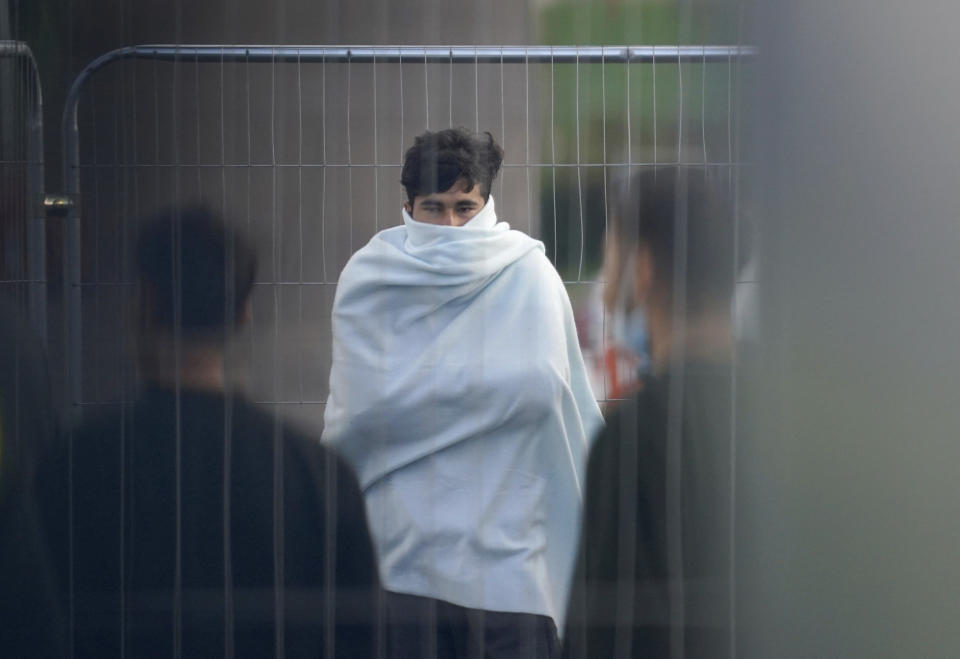 People thought to be migrants walk inside the Manston immigration short-term holding facility located at the former Defence Fire Training and Development Centre in Thanet, Kent, England, Tuesday, Nov. 1, 2022. (Gareth Fuller/PA via AP)