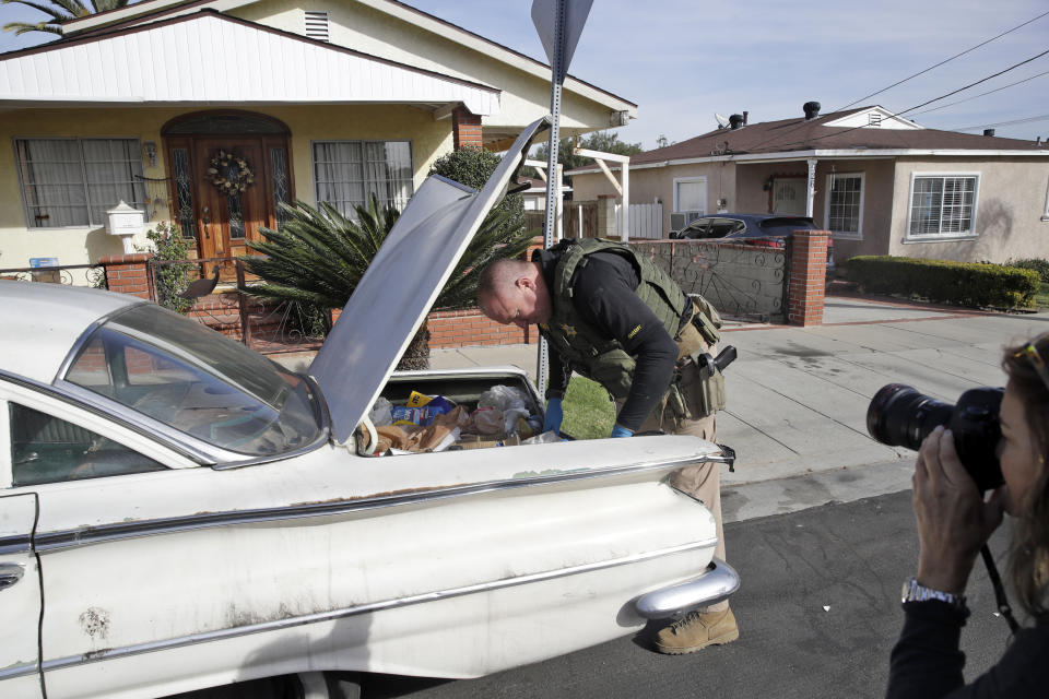 A member of the Los Angeles Sheriffs Dept. searches a vehicle during an investigation outside of a home in connection with a a cold case Wednesday, Feb. 5, 2020, in Los Angeles. Search warrants were served Wednesday at locations in California and Washington state in the investigation of the disappearance of Kristin Smart, the California Polytechnic State University, San Luis Obispo student who disappeared in 1996. (AP Photo/Marcio Jose Sanchez)