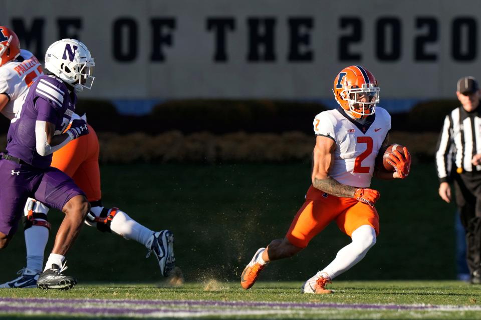 Illinois running back Chase Brown (2) runs past Northwestern defensive back Devin Turner during the first half of an NCAA college football game in Evanston, Ill., Saturday, Nov. 26, 2022. (AP Photo/Nam Y. Huh)