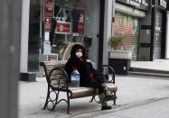 A woman wearing a mask to help protect against the spread of coronavirus, rests in a deserted street after shopping for food during a two-day weekend curfew, in Ankara, Turkey, Sunday, Jan. 24, 2021. Turkey has passed the milestone 25,000 COVID-19 deaths on Sunday. (AP Photo/Burhan Ozbilici)