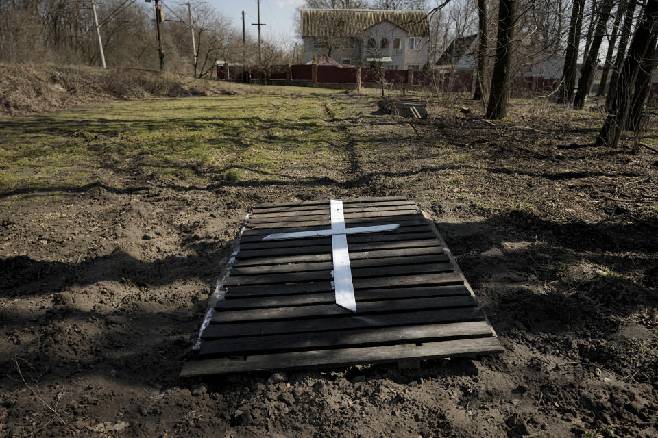 Natalia Vlasenko buried her husband, Pavlo Vlasenko, in her yard under part of a fence, seen in this Monday, April 4, 2022, photo, in Bucha, Ukraine. Russian soldiers beat Pavlo Vlasenko to death and then set his body on fire. Days after Vlasenko buried her husband, she discovered the body of her grandson, Dmytro Chaplyhin, who was known as Dima, at a Russian headquarters at 144 Yablunska Street. Dima was one of at least nine men Russian soldiers picked up during a Mar. 4 sweep and later executed. (AP Photo/Vadim Girda)