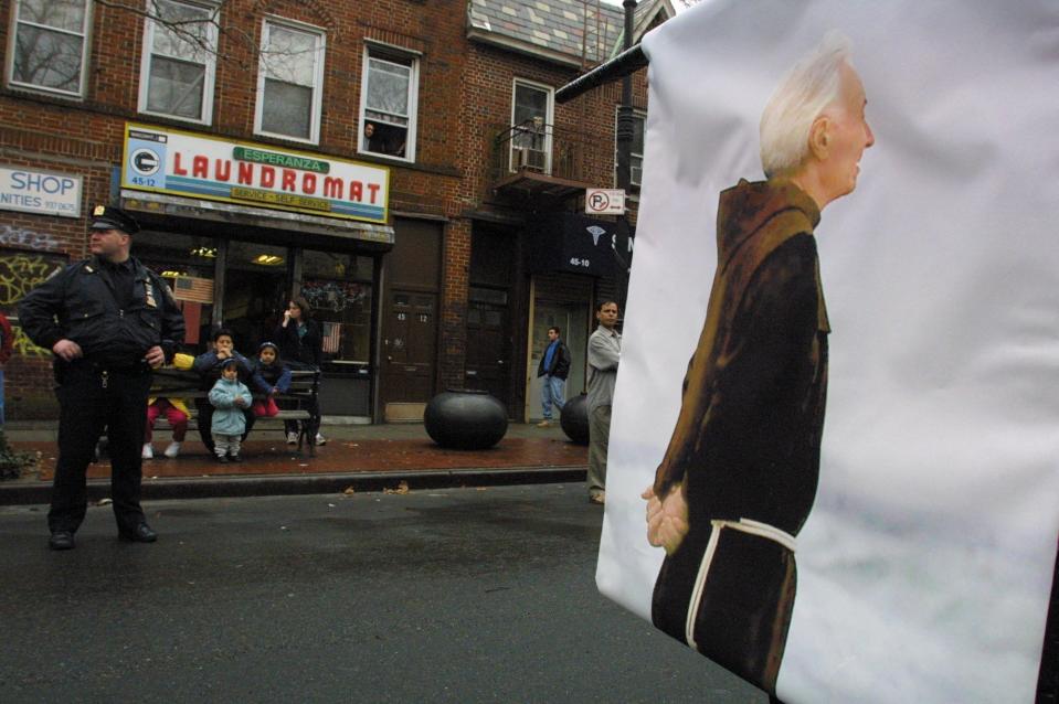 FILE - In this Sunday, March 3, 2002 file photo, a banner printed with a photograph of the late Father Mychal Judge is carried down Skillman Avene in the Queens borough of New York, during an early St. Patrick's Day parade that honored the fire department chaplain killed during the Sept. 11 terrorist attack on the World Trade Center. The third annual parade included groups of various nationalities plus some marchers, such as gays, who would not normally be represented in the city's more traditional parade on March 17th. (AP Photo/Tina Fineberg, File)