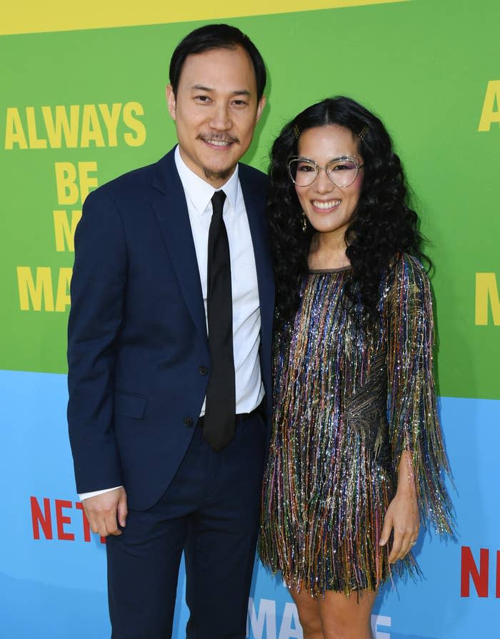 Ali Wong and Justin Hakuta on the red carpet at the premiere of "Always Be My Maybe". Justin is wearing a suit and tie and Ali is wearing a multi-colored fringe dress that hits above the knees