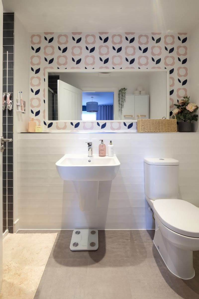 gloating sink vanity and white toilet with pop art flower wall paper behind mirror and white subway tile on wall