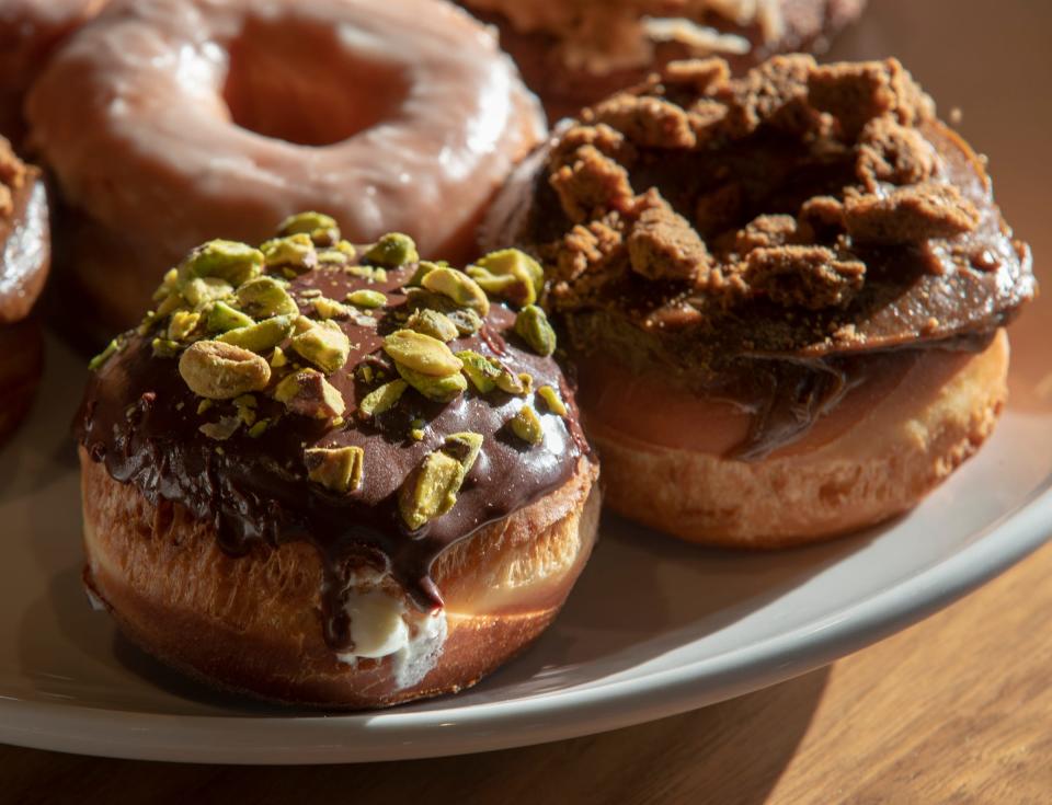 Pistachio-topped cannoli, cookie butter doughnuts and glazed doughnuts at Doughnuts & Dragons, Indianapolis, Tuesday, Oct. 15, 2019. The business is a concept bakery that serves gourmet doughnuts and coffee as well as beer and wine, and has spaces designed for people to sit and converse or play one of the provided games.