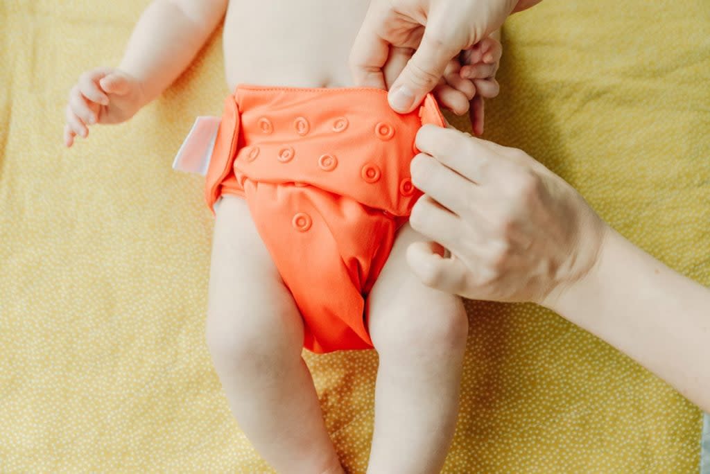 A woman change a baby's cloth diaper.