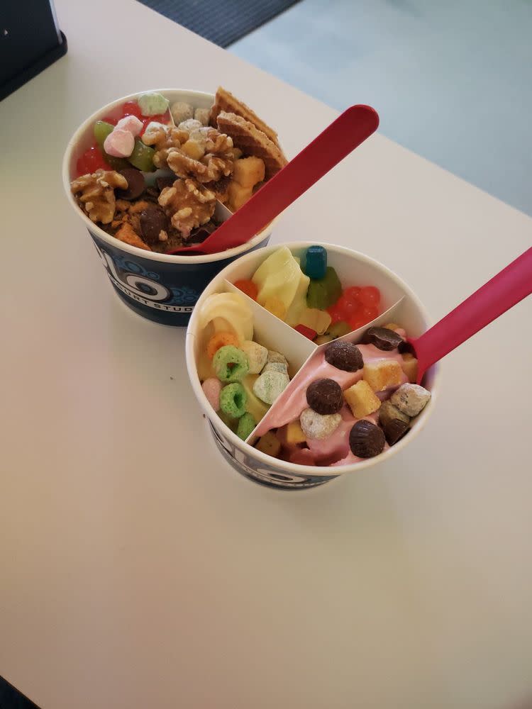 Two cups of frozen yogurt with lots of sweet toppings from Olo Dessert Studio